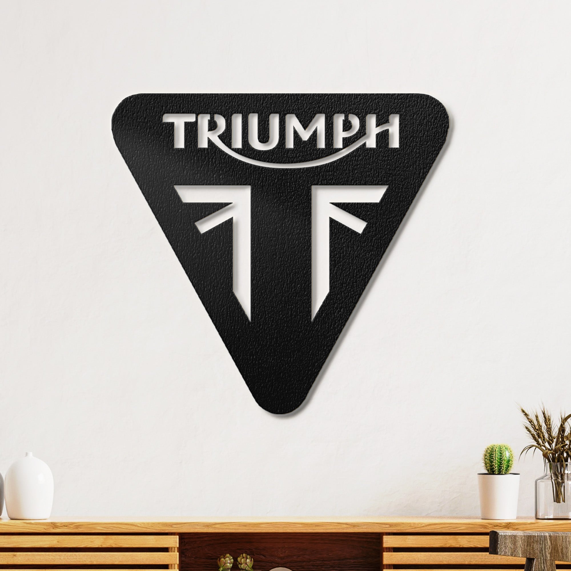 Close-up of the Triumph brand name on a metal sign with subtle lighting.