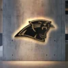 Black metal Carolina Panthers logo wall art with golden backlight.