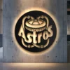 Black metal Houston Astros logo wall art with bright LED backlight on a concrete wall.