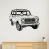 Black metal International Harvester Scout wall art on a white wall above a wooden cabinet.