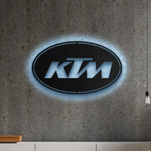 Black metal KTM logo wall art with blue LED backlight on a concrete wall.