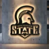 Black metal Michigan State Spartan helmet logo wall art with bright LED backlight.