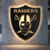 Oakland Raiders shield logo metal wall art with warm LED backlighting.