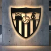 Black metal Sevilla FC shield logo wall art with bright LED backlighting.