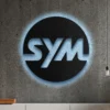 Black metal Sym logo wall art with blue LED backlight on a concrete wall.