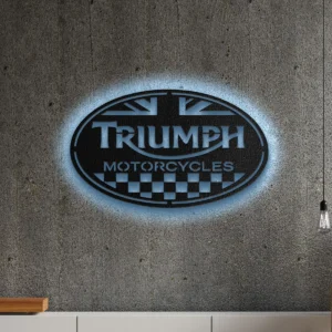 Black metal Triumph Motorcycles logo wall art with blue LED backlighting on a concrete wall.