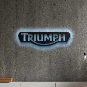 Black metal Triumph logo wall art with blue LED backlight on a concrete wall.